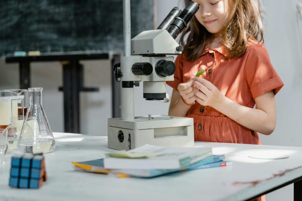 Young girl exploring science with a microscope and lab equipment indoors.